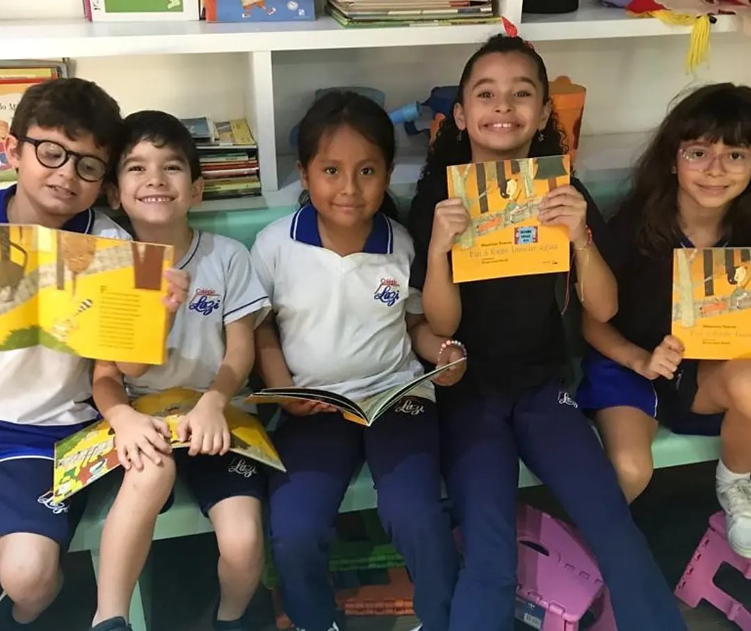 Alunos com livros na sala de leitura